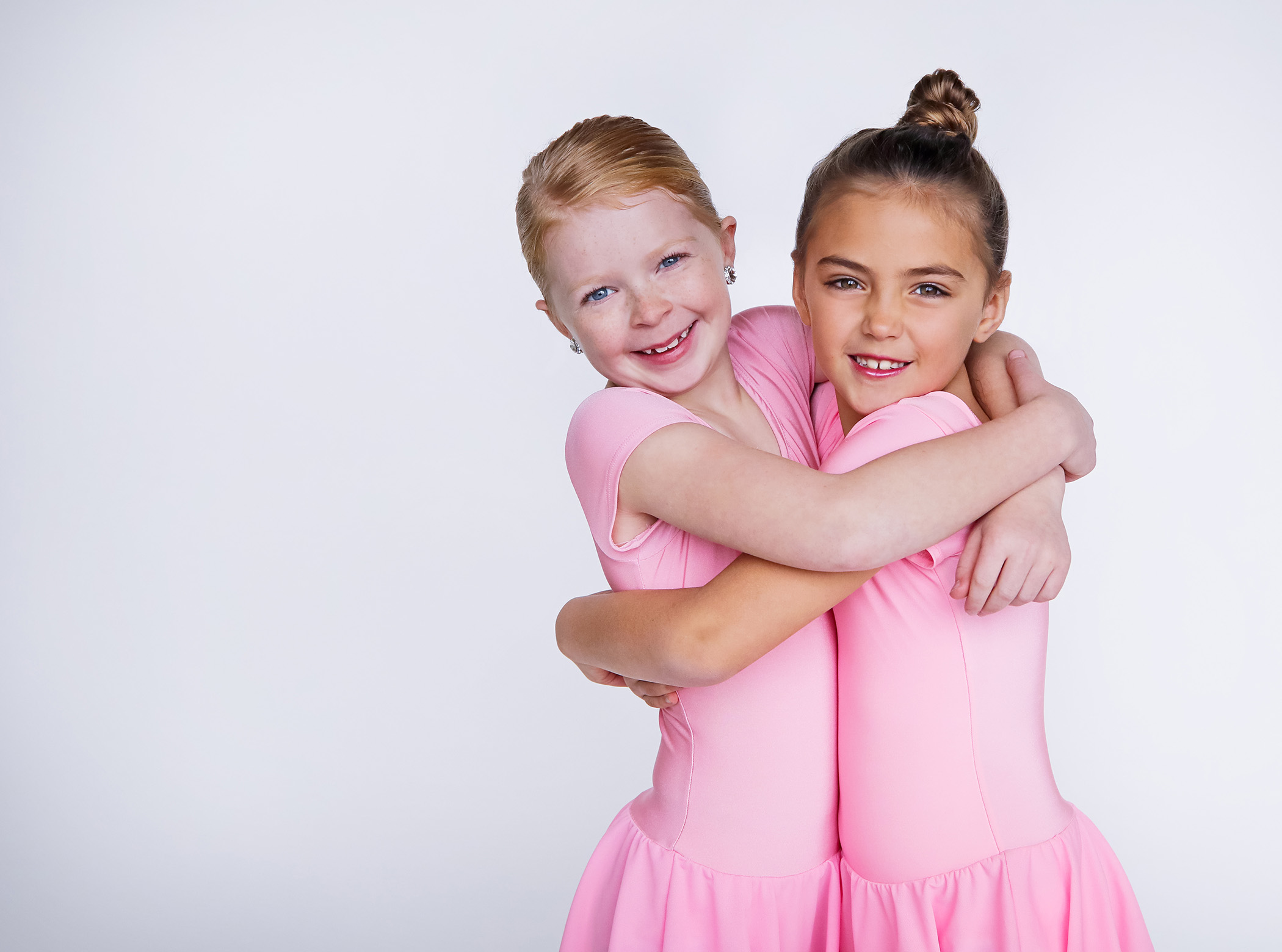 two young dancers in pink hugging